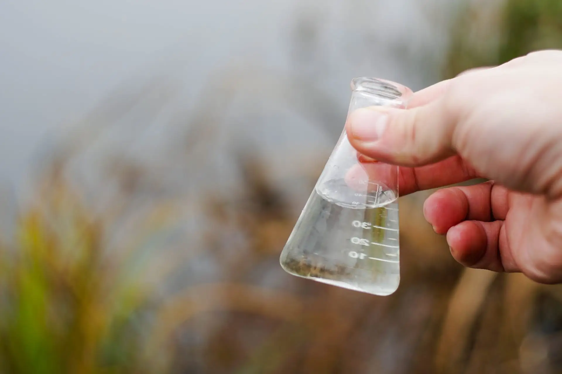 Inspector holding a flask of river water sample for testing, Oakwater Laboratories
